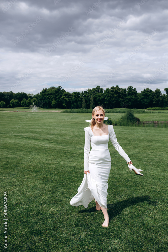 The bride runs barefoot on a green meadow. Summer day. The bride runs barefoot on a green meadow. Summer day.