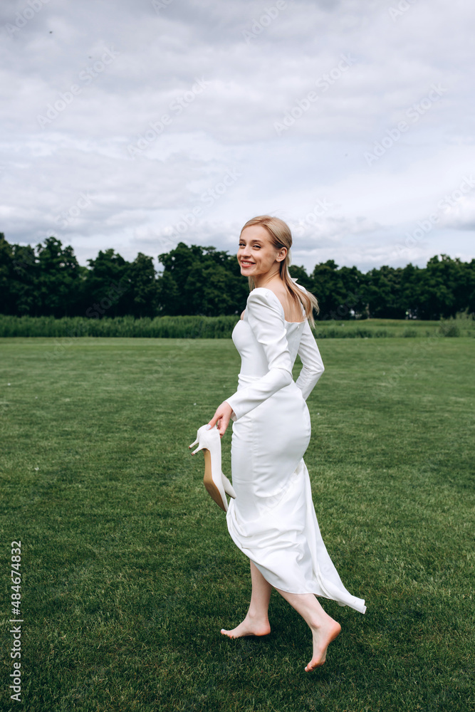 The bride runs barefoot on a green meadow. Summer day. The bride runs barefoot on a green meadow. Summer day.