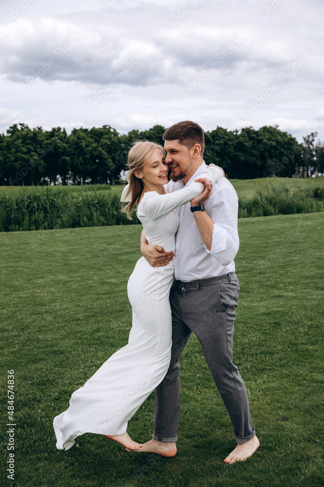 The newlyweds frolic barefoot on a green meadow. Summer day. The newlyweds frolic barefoot on a green meadow. Summer day.