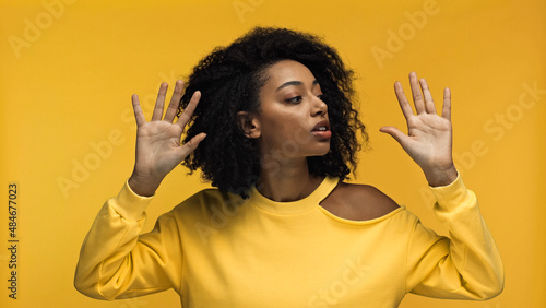Bild auf Leinwand pretty young african american woman showing hands palms while performing mime acting isolated on yellow