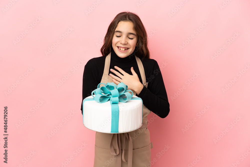 Little Pastry chef holding a big cake isolated on pink background smiling a lot Little Pastry chef holding a big cake isolated on pink background smiling a lot