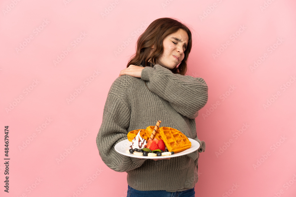 Little girl holding waffles isolated on pink background suffering from pain in shoulder for having made an effort Little girl holding waffles isolated on pink background suffering from pain in shoulder for having made an effort