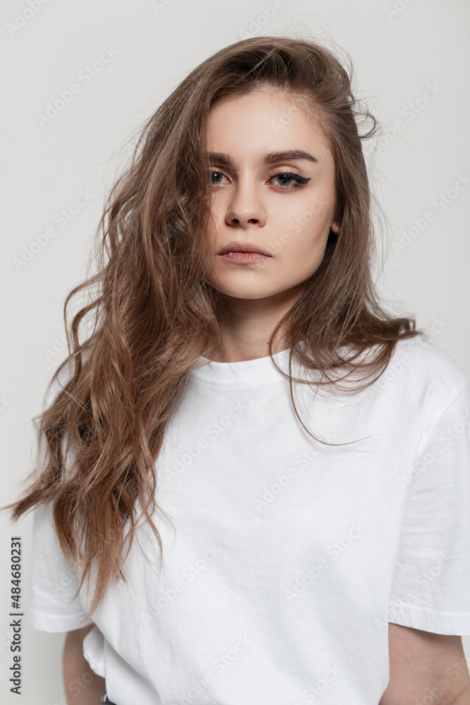 Studio portrait of a beautiful young girl with her hair in a white fashionable T-shirt on a white background Studio portrait of a beautiful young girl with her hair in a white fashionable T-shirt on a white background