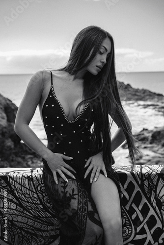 Sexy brunette woman with long hair posing in black fashionable swimsuit outdoor