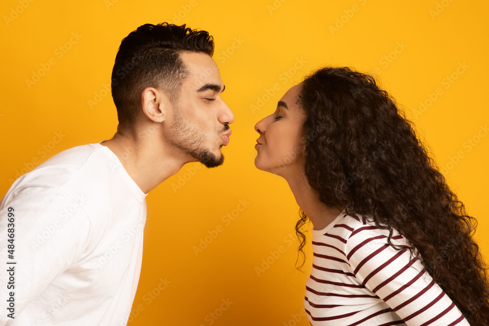 Cheerful Young Arab Couple Reaching Each Other With Lips, Ready To Kiss