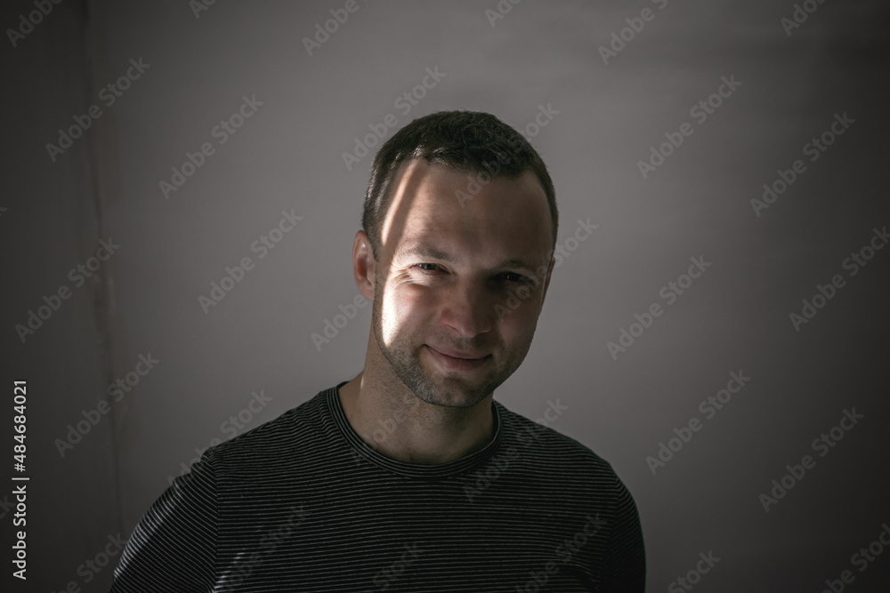 Portrait of young smiling man standing in shadow