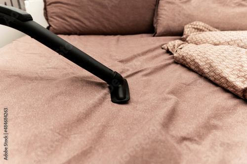 Vacuum the bed. Home cleaning concept. . Upholstered furniture. Cleaning conceptHouse, apartments, hotels. bed cleaning. photo