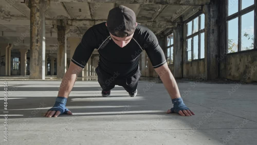 Boxer doing push-ups in abandoned building. MMA fighter training in elastic bandages. Sport concept in slow motion Boxer doing push-ups in abandoned building. MMA fighter training in elastic bandages. Sport concept in slow motion