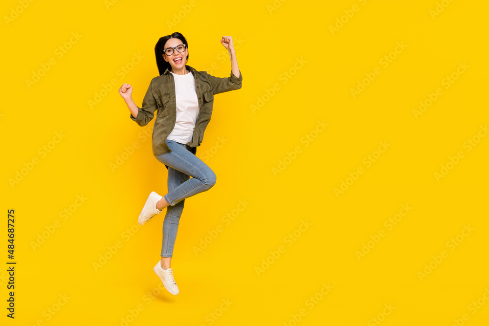 Full size photo of celebrate young lady jump wear eyewear shirt jeans sneakers isolated on yellow background