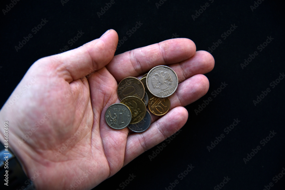 An outstretched hand with coins on a black background An outstretched hand with coins on a black background
