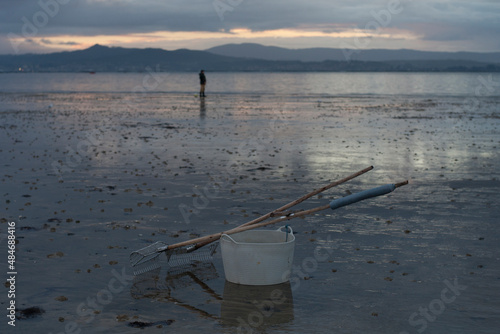 Work utensils of a shellfisher of clams and cockles on a beach in Galicia at dawn photo