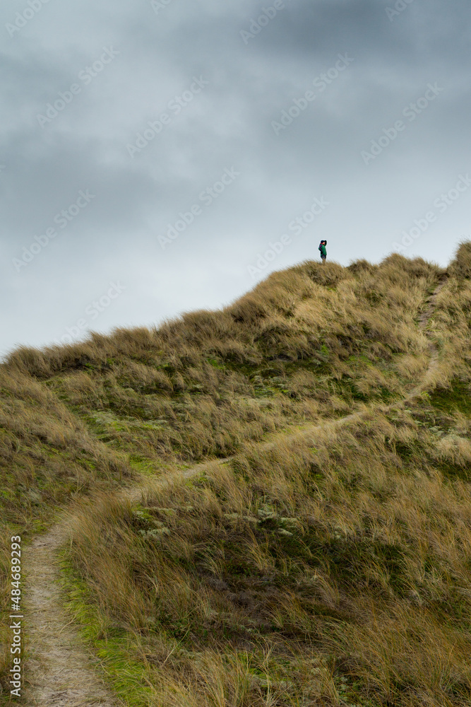 Person standing on a high dune in Denmark during rainy weather in wintertime