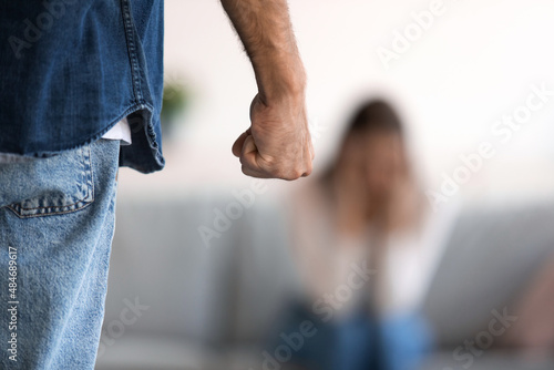 Fist of angry aggressive millennial caucasian husband and crying wife afraid of domestic violence