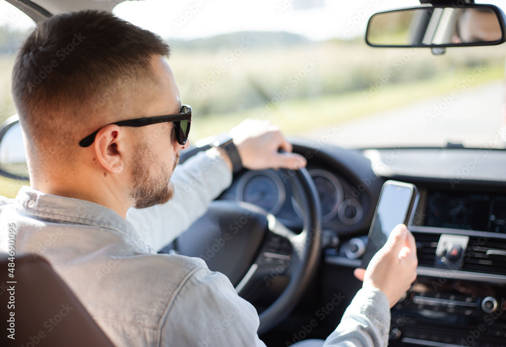 Unrecognisable driver guy using mobile phone with screen sitting in automobile. Unrecognisable driver guy using mobile phone with screen sitting in automobile.