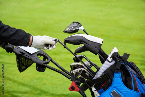 Golfer removes a golf club from the bag to shoot the ball from the fairway.