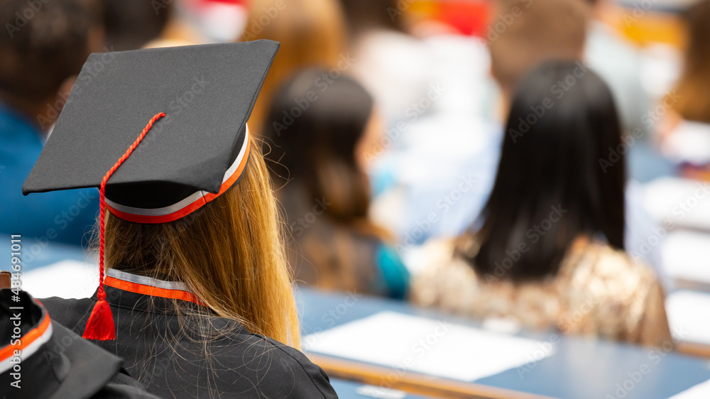 Remise de diplômes à l'université - Jeune étudiante portant une coiffe universitaire - obrazy, fototapety, plakaty 
