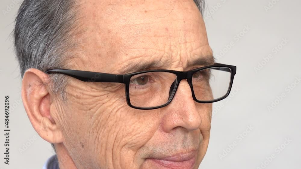 An elderly man squints, puts on his glasses An elderly man squints, puts on his glasses