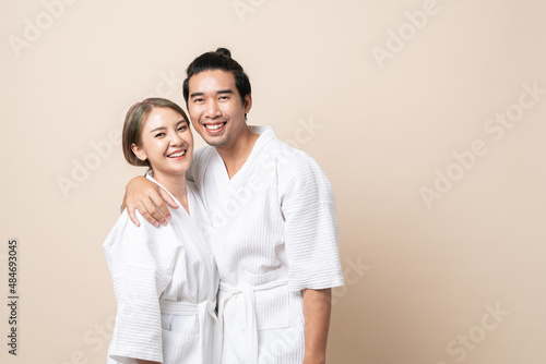 Asian couple in bathrobe or spa suit smile happy together on brown isolated studio background.