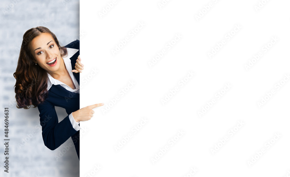 Happy excited woman in black confident suit showing pointing blank white banner signboard. Business and advertising concept. Copy space empty place. White bricks loft wall background. Happy excited woman in black confident suit showing pointing blank white banner signboard. Business and advertising concept. Copy space empty place. White bricks loft wall background.