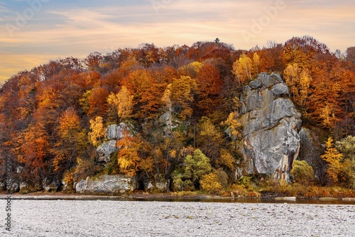 Rocky cliff with yellowed trees and mountain river in autumn
