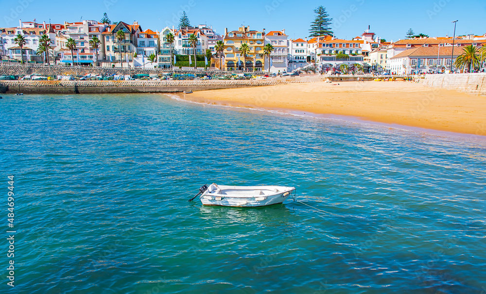 Fototapeta premium Panoramic view of sandy bay from city - Cascais, portuguese coast at Atlantic. Fishing boat with fishing net and equipment 