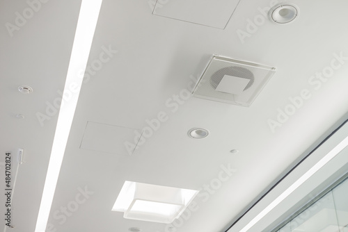 White plasterboard ceiling in administrative and public building with ventilation  lamps and speakers