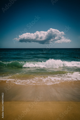 Lone Cloud Hovers over Blue Pacific waves and sand photo