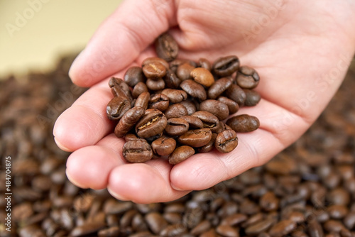 Roasted coffee beans in a woman's hand.