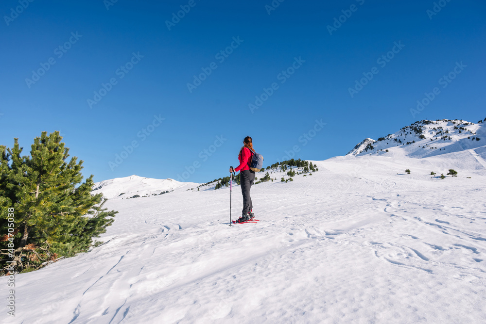 Woman practicing winter sports. Snowshoeing on a sunny day Woman practicing winter sports. Snowshoeing on a sunny day