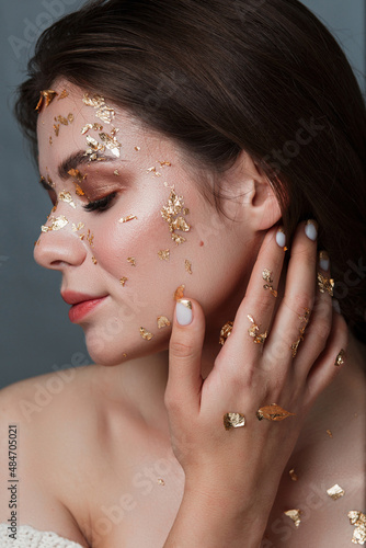 Beauty portrait of a girl in profile with beautiful golden nails photo