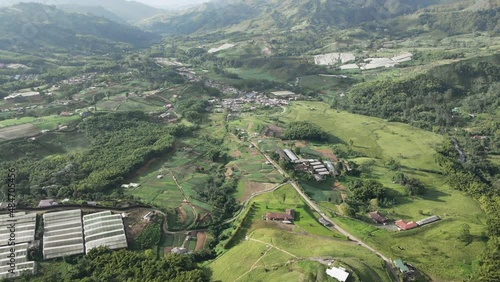 Vista de pueblo en un valle rodeado por montañas y campos de cultivo.
