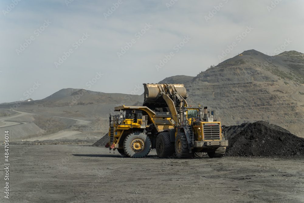 A loader loads ore into a dump truck at the gold mine site.