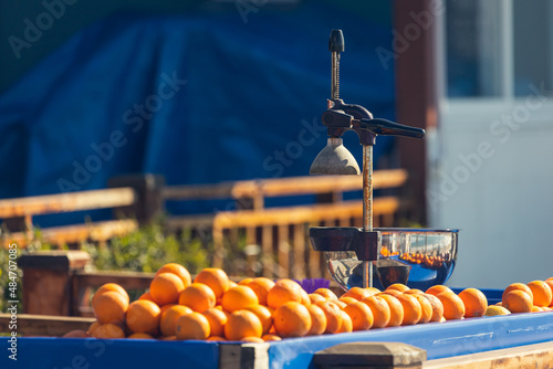 close-up of a manual metal juicer and a lot of fresh oranges on the store counter