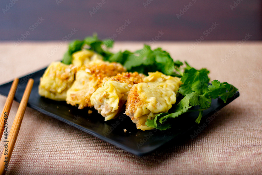 Chinese Steamed Dumpling served in a black plate on a wooden table. along with cilantro. Chinese Steamed Dumpling served in a black plate on a wooden table. along with cilantro.