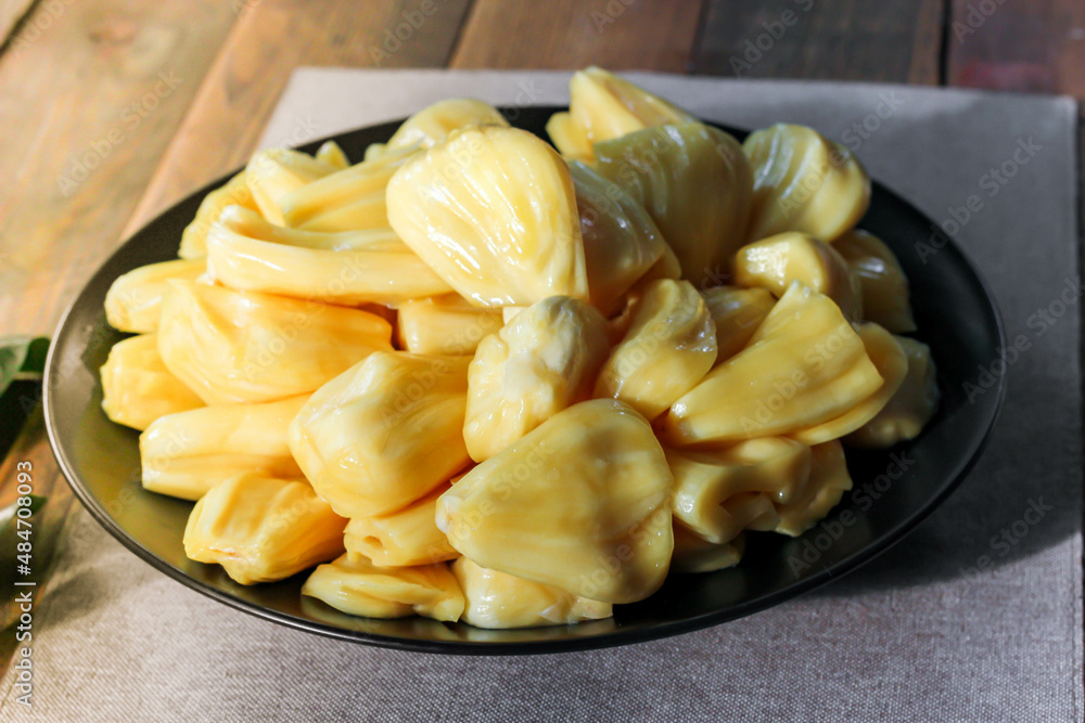 Thai fruit, fresh jackfruit placed in a black plate on a wooden table. Thai fruit, fresh jackfruit placed in a black plate on a wooden table.