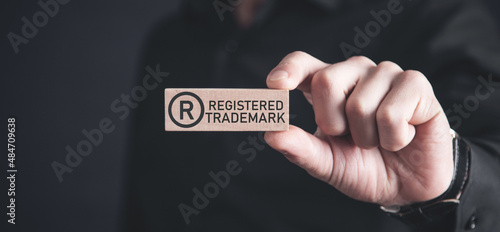 Male hand showing R-Registered trademark on wooden block. photo