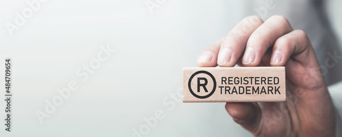 Male hand showing R-Registered trademark on wooden block. photo