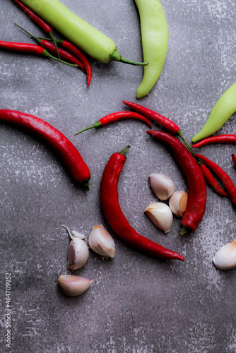 Red chilli and green chilli, garlic spread on the gray table ready to cook in the kitchen.