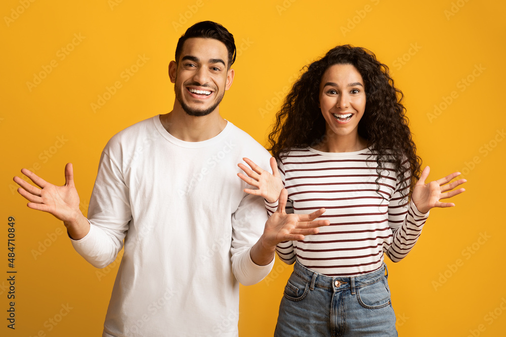 Portrait Of Joyful Arab Couple Spreading Hands With Excitement Over Yellow Background Portrait Of Joyful Arab Couple Spreading Hands With Excitement Over Yellow Background