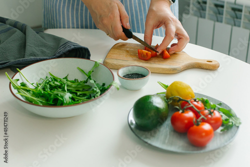 Woman preparing vegetable salad with tomato in the kitchen. Healthy food vegan salad. Mindful eating