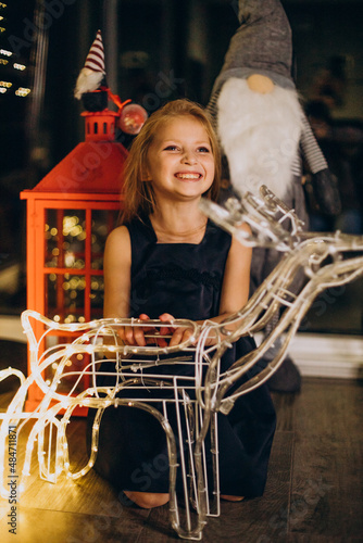 Cute little girl sitting by the christmas lights in the eve