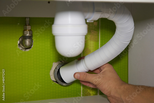 Fotografie installs a siphon pipe,men's hands install a washbasin siphon