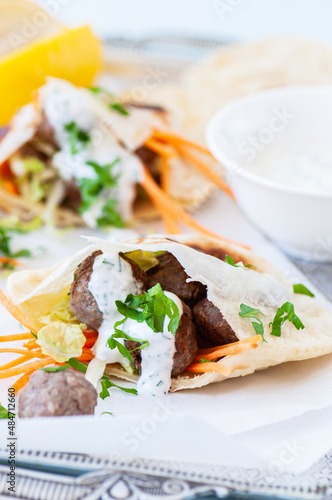 Homemade lamb meatballs in pita flatbread with spicy yoghurt sauce. Close up.