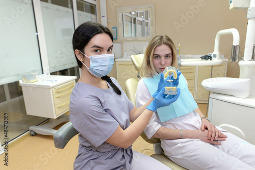The dentist shows the patient an artificial model of teeth