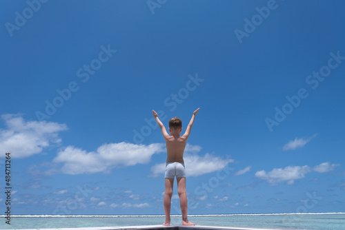 Boy on beach hold hands arms up