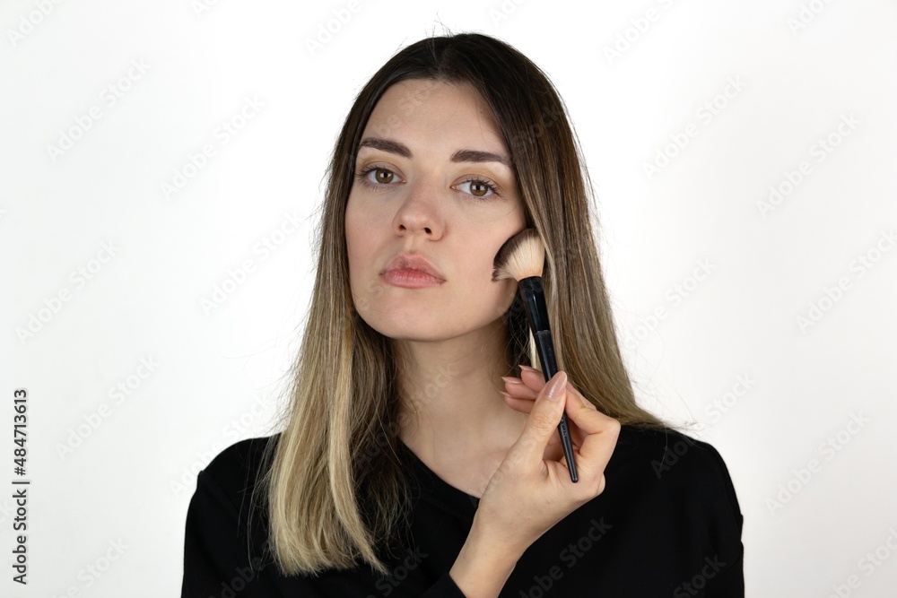 Photo of young girl with flawless skin holding cosmetics brush on white background. Skin care and beauty concept. Photo of young girl with flawless skin holding cosmetics brush on white background. Skin care and beauty concept.