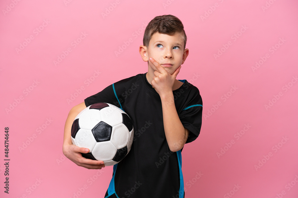 Little caucasian football player boy isolated on pink background having doubts Little caucasian football player boy isolated on pink background having doubts