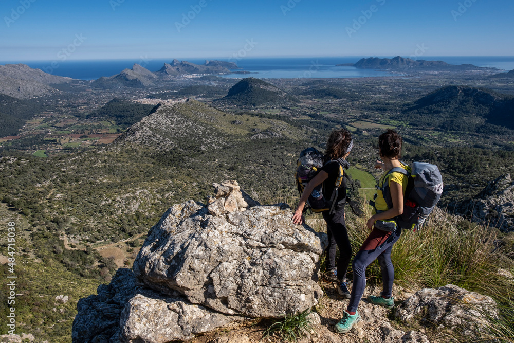 hikers ascending Cucuia de Fartaritx with Alcudia bay in the background, Pollença, Mallorca, Balearic Islands, Spain