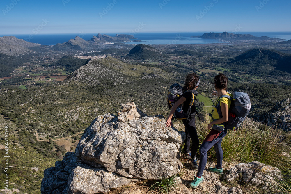 Fototapeta premium hikers ascending Cucuia de Fartaritx with Alcudia bay in the background, Pollença, Mallorca, Balearic Islands, Spain