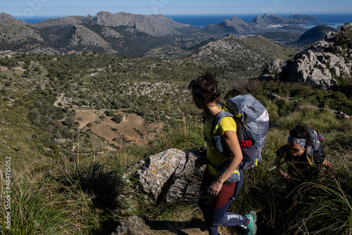 hikers ascending Cucuia de Fartaritx with Alcudia bay in the background, Pollença, Mallorca, Balearic Islands, Spain